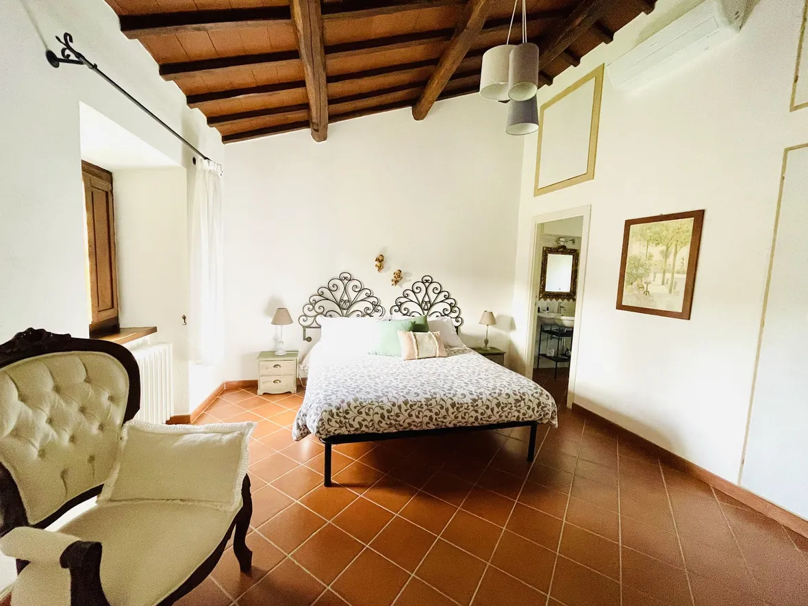 Camera con poltrona e letto sotto il soffitto in legno